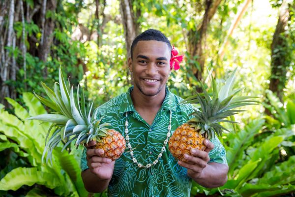 A happy man holding two pineapples at Savusavu