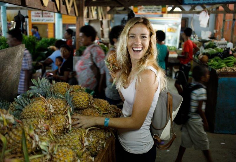 A woman posing next to pineapples at Savusavu Markets