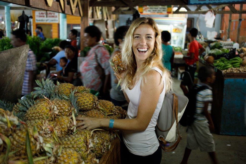 A woman posing next to pineapples at Savusavu Markets