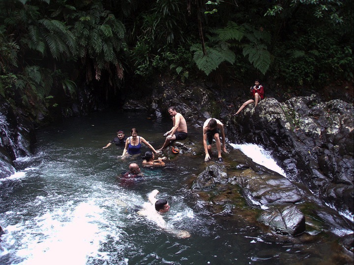 A group of tourists enjoy a waterfall behind Daku Resort