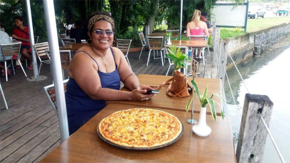 A woman sits with a pizza at the Captain's Cafe, Savusavu.