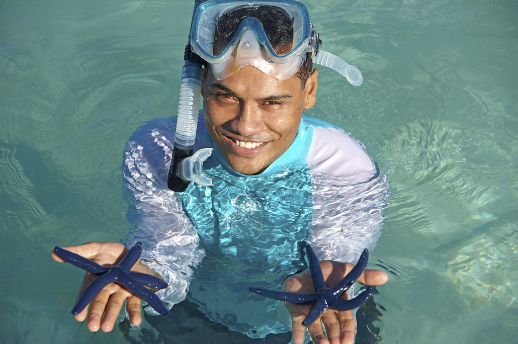 A snorkeler holds some local starfish.